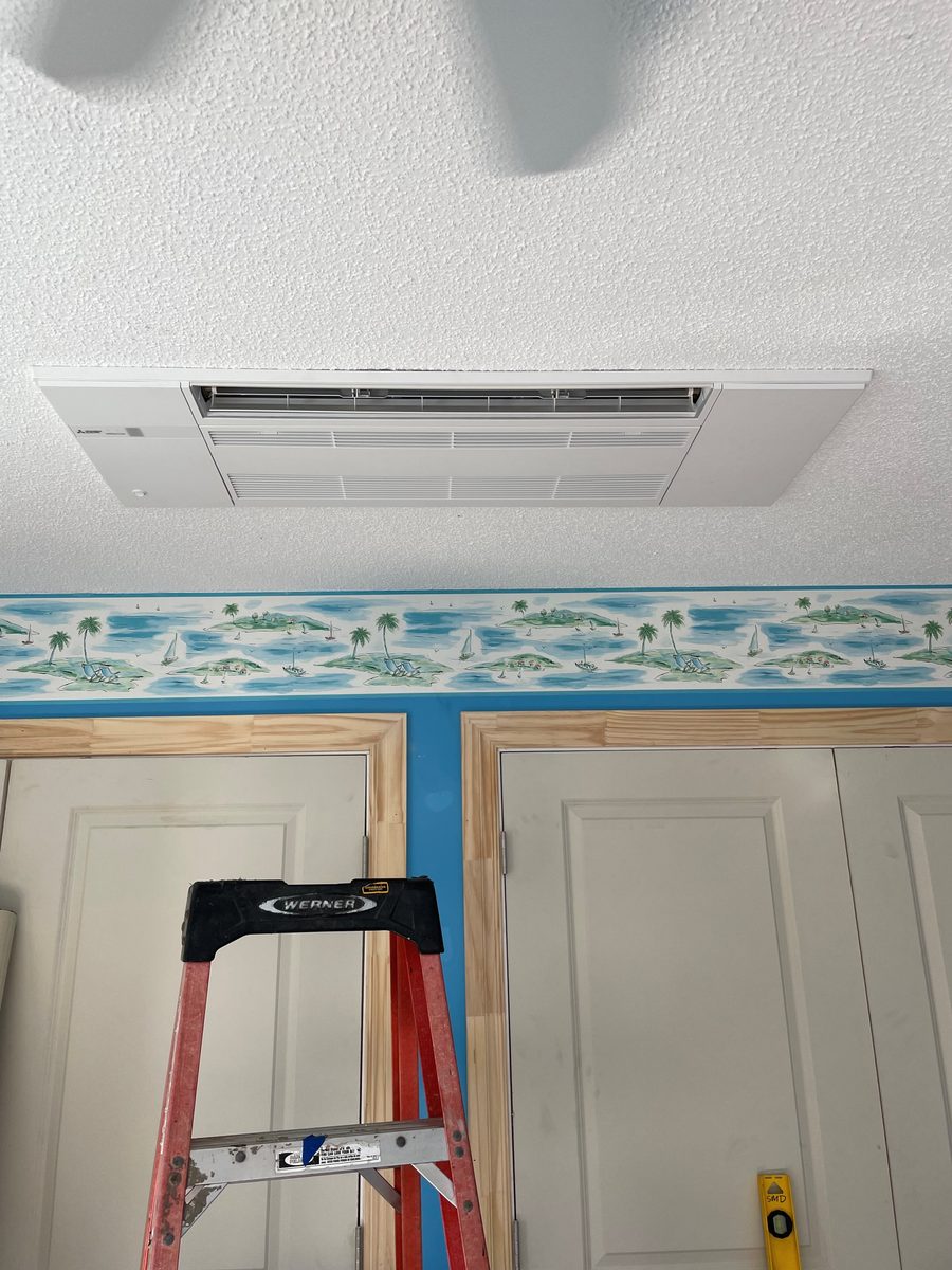 Mitsubishi ceiling cassette mini-split installed flush in the ceiling of a Panama City Beach vacation home, red ladder visible below