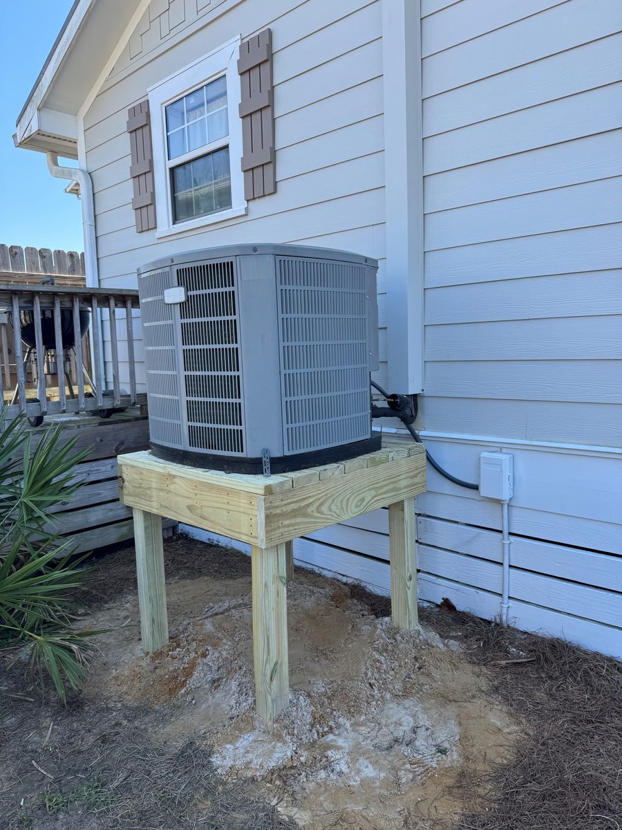 Trane outdoor condensing unit elevated on a custom pressure-treated wooden deck next to a Florida coastal home with palm tree