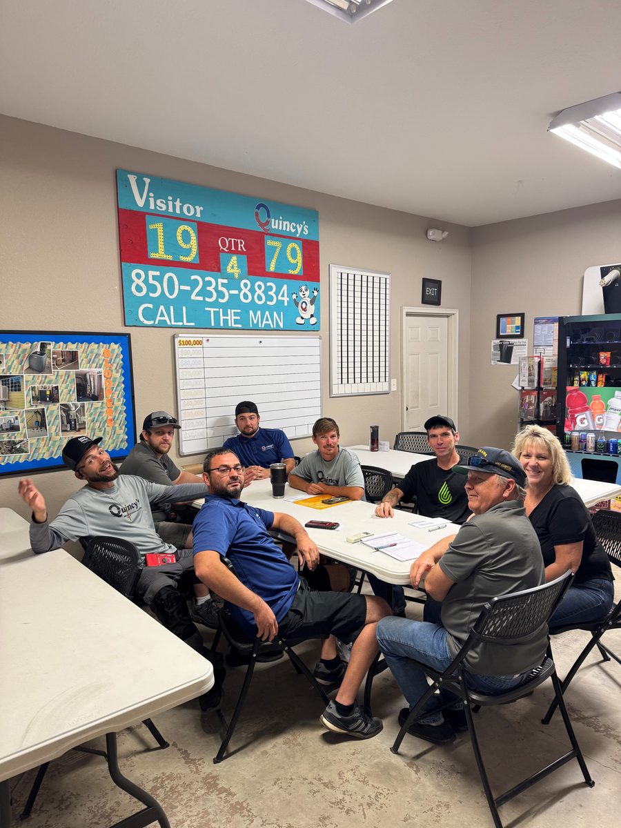 The Quincy's Heating & Air team around the table in their training room, including co-owner Crystal Walker